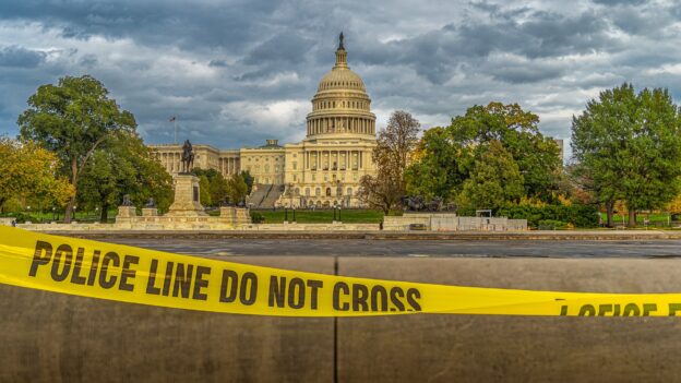 View of the Capitol in Washington with a police barrier tape in front, stating: «Police line – Do not cross».